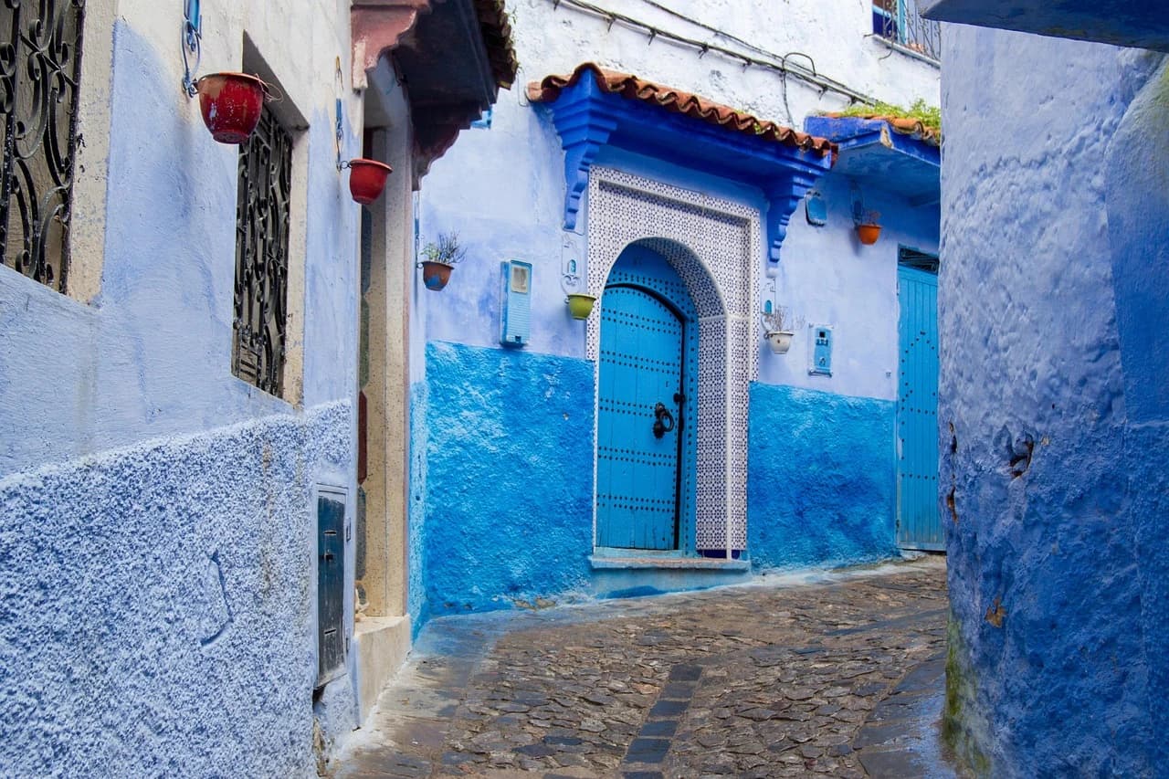 Ruelles bleues emblématiques de Chefchaouen au cœur de la médina, montagnes du Rif en arrière-plan