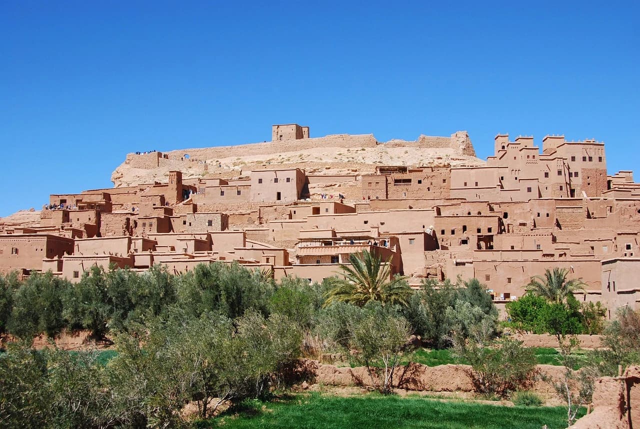 Kasbah Taourirt à Ouarzazate au coucher du soleil — tours crénelées en pisé ocre dominant la palmeraie de la vallée du Drâa